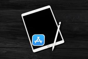 kharkiv, ucrania - 27 de enero de 2022 nuevo ipad de apple y lápiz de apple y logotipo azul de la tienda de aplicaciones sobre fondo negro. Apple Inc. es una empresa de tecnología americana foto