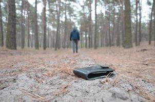 Young man loses his purse with euro money bills on Russian autumn fir wood path. Carelessness and losing wallet concept photo