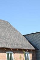 Flexible shingles of bitumen roofing surface on the brick house photo