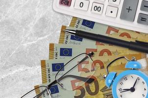 50 euro bills and calculator with glasses and pen. Business loan or tax payment season concept. Time to pay taxes photo