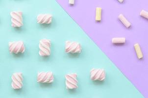 Colorful marshmallow laid out on violet and blue paper background. pastel creative textured pattern. minimal photo