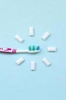 Toothbrush and chewing gums lie on a pastel blue background. Top view, flat lay. Minimal concept photo