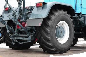 Wheels of back view of new tractor in snowy weather. Agricultural vehicle back photo