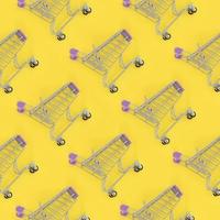 Shopping addiction, shopping lover or shopaholic concept. Many small empty shopping carts perform a pattern on a pastel colored paper background. Flat lay composition, top view photo