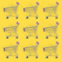Shopping addiction, shopping lover or shopaholic concept. Many small empty shopping carts perform a pattern on a pastel colored paper background. Flat lay composition, top view photo
