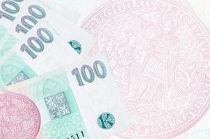 100 Czech korun bills lies in stack on background of big semi-transparent banknote. Abstract business background photo