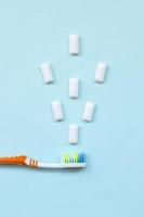 Toothbrush and chewing gums lie on a pastel blue background. Top view, flat lay. Minimal concept photo