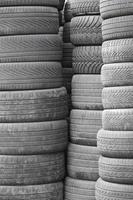 Old used tires stacked with high piles in secondary car parts shop garage photo