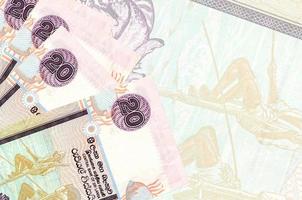 20 Sri Lankan rupees bills lies in stack on background of big semi-transparent banknote. Abstract business background photo