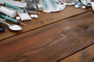 A lot of narcotic substances and devices for the preparation of drugs lie on an old wooden table photo