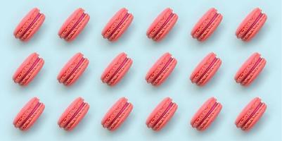Pink dessert cake macaron or macaroon on trendy pastel blue background top view. Flat lay pattern composition photo