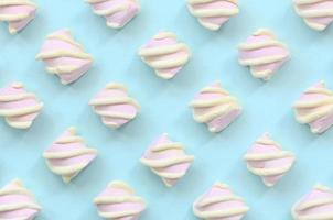 Colorful marshmallow laid out on blue paper background. pastel creative textured pattern. minimal photo