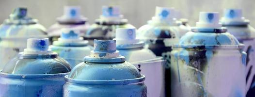 A lot of dirty and used aerosol cans of bright blue paint. Macro photograph with shallow depth of field. Selective focus on the spray nozzle photo
