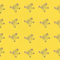 Shopping addiction, shopping lover or shopaholic concept. Many small empty shopping carts perform a pattern on a pastel colored paper background. Flat lay composition, top view photo