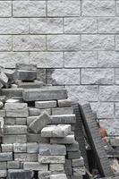 A large pile of disassembled paving tiles against the wall of light bricks photo