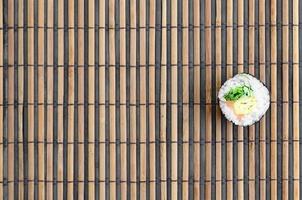 Sushi roll lie on a bamboo straw serwing mat. Traditional Asian food. Top view. Flat lay minimalism shot with copy space photo