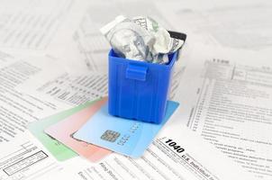 1040 Individual income tax return form and crumpled hundred dollar bill in trash bin on credit cards photo