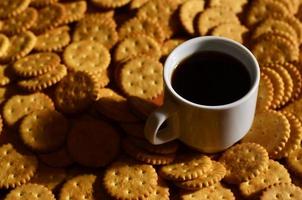 taza de café pequeña y galleta salada foto