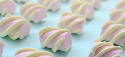 Colorful marshmallow laid out on blue paper background. pastel creative textured pattern. Perspective macro shot photo