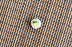 Sushi roll lie on a bamboo straw serwing mat. Traditional Asian food. Top view. Flat lay minimalism shot with copy space photo