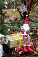 Christmas gnome sitting on boxes with gifts near the Christmas tree photo