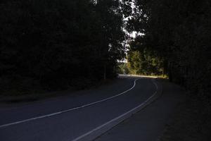 Light at end of road. Highway in countryside. Road with white stripe. Track outside city. photo