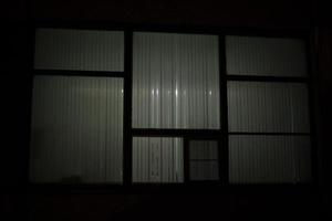 gran ventana por la noche. ventana en edificio. las persianas cubren la luz de la lámpara. foto