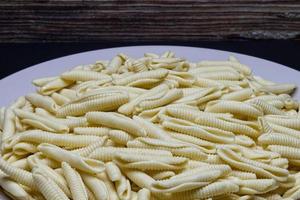 Uncooked Italian Maccheroni al pettine pasta on black background. photo