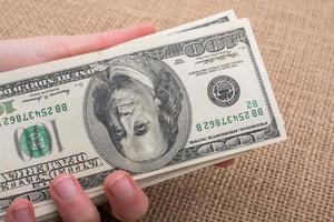 mano que sostiene el paquete de billetes de dólar estadounidense en la mano foto