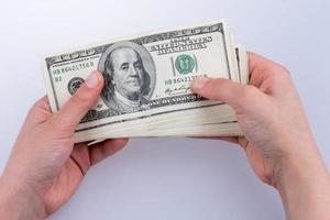 mano humana sosteniendo billetes de dólar americano sobre fondo blanco