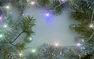 Christmas background. Christmas tree branches, light garland, tinsel and Christmas balls. photo