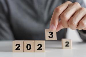 Man hand putting wooden cube block to change 2022 year to 2023 year. start to year 2023. happy new years concept. photo