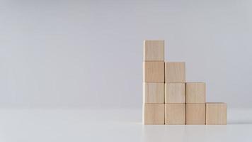 pila de bloques de cubo de madera como escalón en la mesa. éxito, subir a la cima, progresión, concepto de crecimiento empresarial. foto