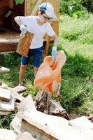 the boy collects garbage in a bag. The child will help with cleaning the territory on the street photo