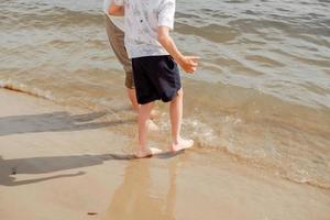 Mother and child walking on a sandy beach. Cool water in the sea. Walk along the beach barefoot. photo