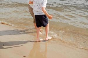 madre e hijo caminando en una playa de arena. agua fresca en el mar. caminar descalzo por la playa. foto