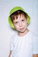 retrato de un niño con un sombrero de Panamá verde, sobre un fondo blanco foto