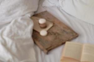 coffee with marshmallows and macaroons, book on a wooden tray, in bed. The photo is out of focus. Aesthetically beautiful frame. Desserts in bed. hot chocolate with marshmallows.