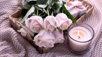 Tray with  bouquet of beautiful pink roses and gift box and burning candle on bed. video