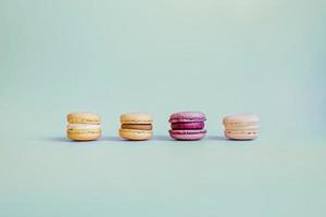 Four colored macaroons on turquoise background. photo