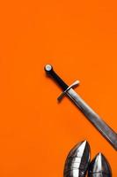 Sabatons and a sword on an orange background. photo