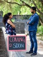 pareja india posando para una sesión de fotos de maternidad. la pareja está posando en un césped con hierba verde y la mujer está faluntando su panza en el jardín lodhi en nueva delhi, india