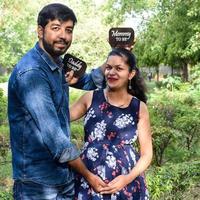 Indian couple posing for maternity baby shoot. The couple is posing in a lawn with green grass and the woman is falunting her baby bump in Lodhi Garden in New Delhi, India photo