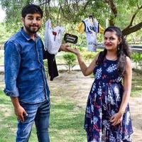 Indian couple posing for maternity baby shoot. The couple is posing in a lawn with green grass and the woman is falunting her baby bump in Lodhi Garden in New Delhi, India photo