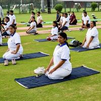 New Delhi, India, June 21 2022 - Group Yoga exercise session for people at Yamuna Sports Complex in Delhi on International Yoga Day, Big group of adults attending yoga class in cricket stadium photo