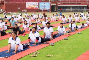 nueva delhi, india, 21 de junio de 2022 - sesión grupal de ejercicios de yoga para personas en el complejo deportivo yamuna en delhi el día internacional del yoga, gran grupo de adultos que asisten a clases de yoga en el estadio de cricket foto