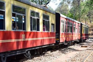 Toy Train moving on mountain slopes, beautiful view, one side mountain, one side valley moving on railway to the hill, among green natural forest. Toy train from Kalka to Shimla in India, Indian Train photo