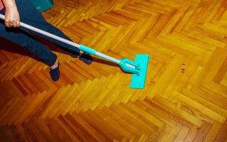 Mop your wood floor. A woman washes the parquet with a mop with a special solution. Housekeeping concept. photo