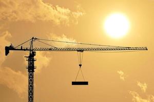 Silhouettes of tower construction cranes with yellow sky at morning time photo