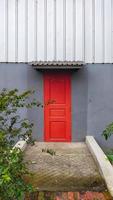 A small red door and a small bridge pathway to the door. photo